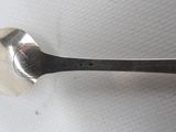 a silver spoon with a black handle sitting on a white surface