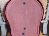 a pink chair with a buttoned back and a chain around the seat