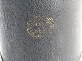 an old black leather cylinder case with a gold trim and a logo on the side