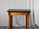 une table en bois avec un plateau en marbre noir, posée sur un parquet