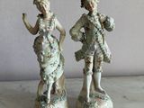 two figurines of a man and a woman standing next to each other