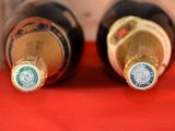 two bottles of wine sitting on a red cloth
