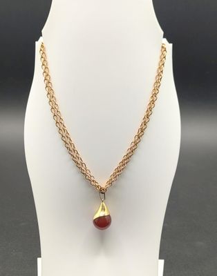 a gold necklace with a red bead and a gold chain