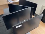 trois écrans d'ordinateur posés sur un bureau dans un bureau
