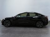 a black tesla model s parked in a room with a white wall