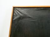 un tableau noir avec un cadre en bois accroché à un mur blanc