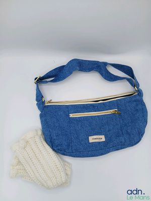 un sac à main bleu et des mitaines posés sur une table blanche