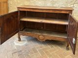 a wooden cabinet with a door open on a brick floor
