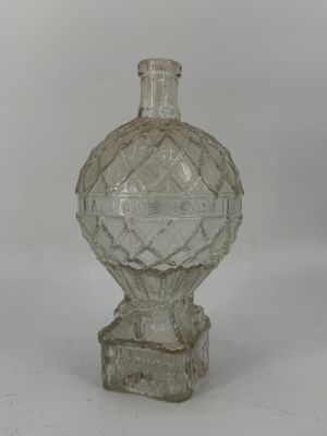 une bouteille en verre transparent avec un fond transparent posée sur une surface blanche