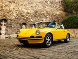 a yellow car parked in front of a stone wall
