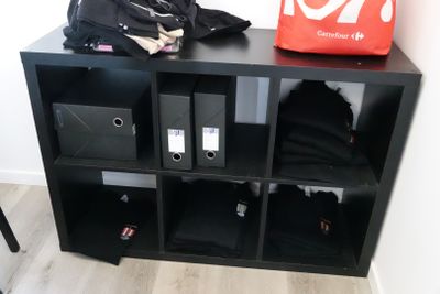 a black bookcase with several bins on top of it
