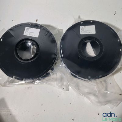 two spools of black pla filamant on a table