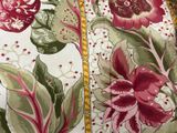 a close up of a bed with a red and green floral comforter