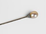 an antique silver spoon with a pearl in it on a white surface