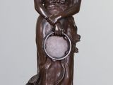 une statue représentant une femme tenant une horloge, posée sur un socle