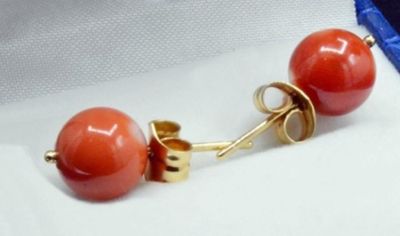 pair of coral colored earrings with gold posts on a white surface