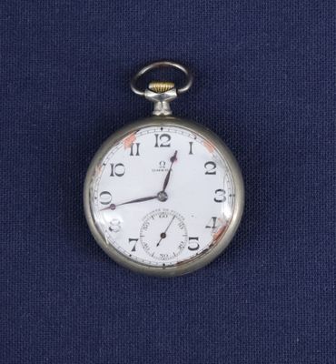 une montre de poche en argent posée sur un tissu bleu
