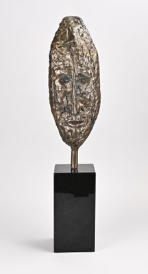 une photo d'une sculpture en bronze représentant un visage, posée sur un socle noir