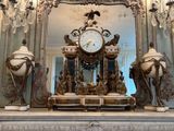 une horloge posée sur une cheminée, devant un miroir
