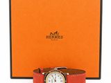 an orange watch with a white face sits in front of an orange box
