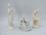 trois figurines blanches représentant des femmes et un homme assis sur une chaise