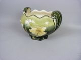 a green vase with white flowers on it on a white surface