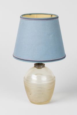 une lampe en verre surmontée d'un abat-jour bleu