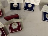 several silver and red boxes with silver coins in them on a table