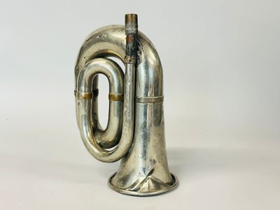 an old silver trumpet sitting on top of a white surface