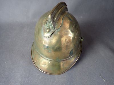 a brass helmet with a metal handle on a gray background