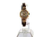 une montre en or posée sur un socle transparent, sur fond blanc