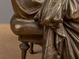 a bronze statue of a woman sitting on a chair