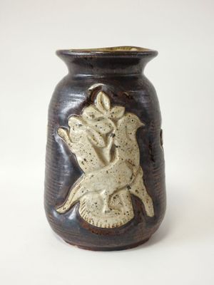 un vase avec un oiseau posé sur une table