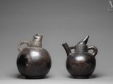 pair of bronze vases with handles and handles on a gray background