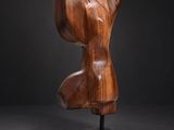 a wooden sculpture of a female torso on a black background