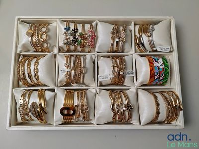 une boîte blanche remplie d'une multitude de bracelets en or et en argent