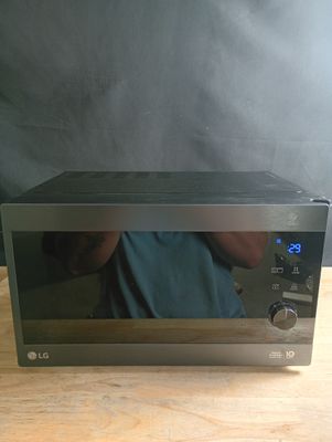 Quelqu'un prend une photo d'un micro-ondes posé sur une table en bois.