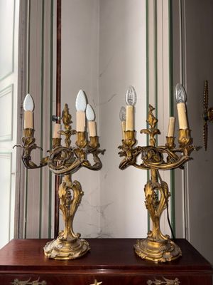 deux chandeliers dorés posés sur une table en bois dans une pièce