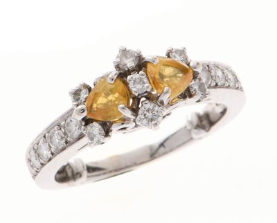 un gros plan d'une bague en diamant sertie de deux saphirs jaunes en forme de poire