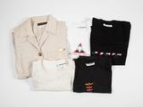three shirts and a jacket sitting on top of a white table