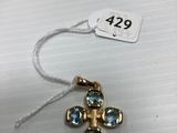 a gold cross charm with blue crystals on a string