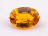 a close up of a yellow sapphire stone on a white surface