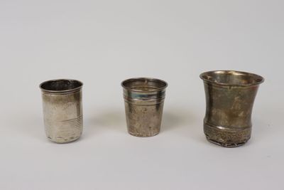 trois tasses en argent posées l'une à côté de l'autre sur une surface blanche