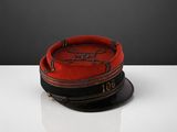 une image représentant un chapeau rouge et noir posé sur une table blanche