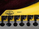 a close up of a yellow guitar neck with black knobs