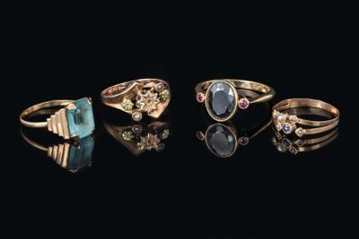 cinq bagues différentes ornées de pierres de couleurs variées sur un fond noir