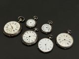 several different types of pocket watches are displayed on a black surface