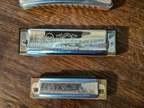 three harmonicas sitting on a wooden table with one of them open