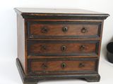 a small wooden chest of drawers on a white surface