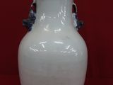 un vase blanc orné de fleurs bleues sur fond rouge